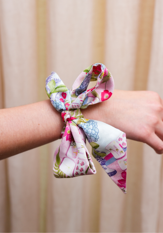 Silk scarflette with pink, green, and purple floral Mahjong tile print tied around wrist.