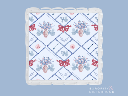 Square acrylic tray with scalloped edges, decorated with blue floral and red bow patterns over white background.