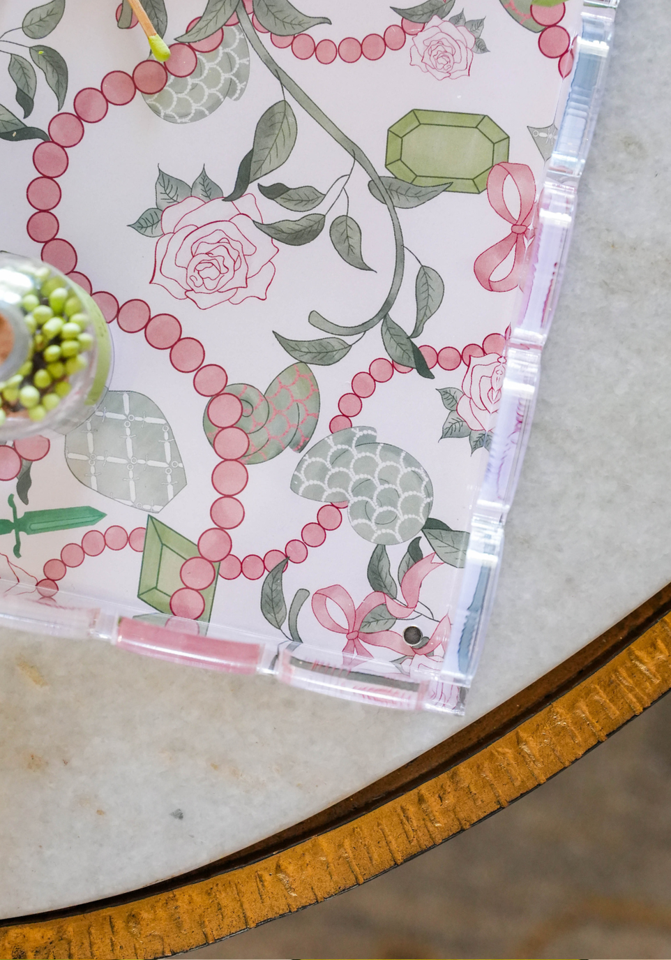 Clear acrylic tray with scalloped edges and pink floral and beaded chain pattern on the base.