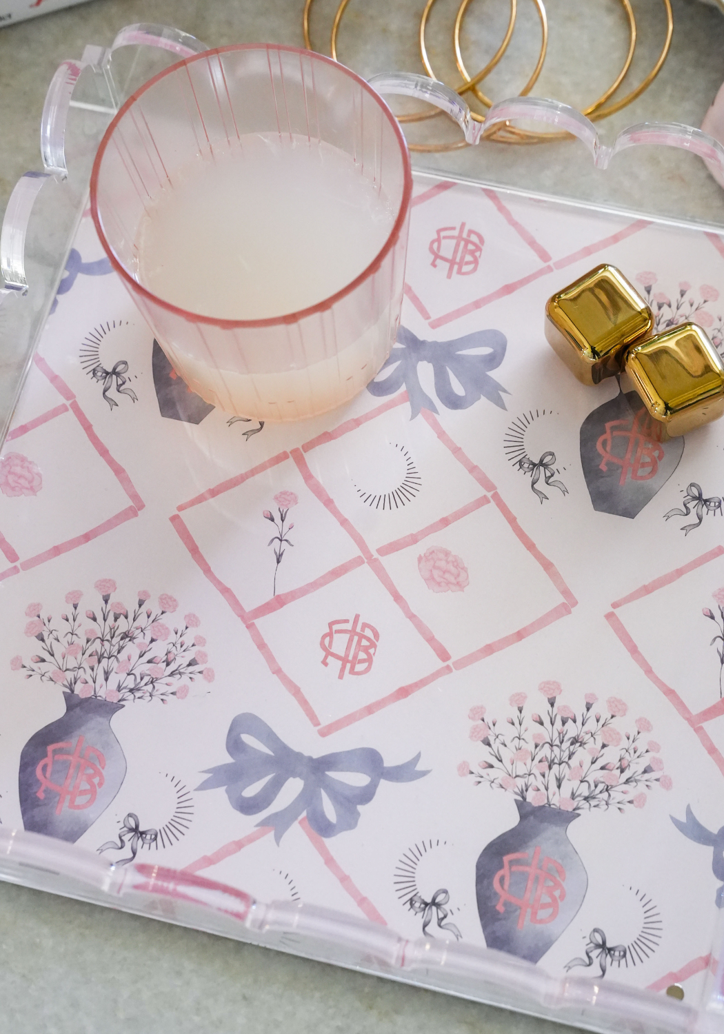 Rectangular tray with scalloped edges, decorated with blue bows, pink florals in blue vases, and geometric patterns on white .