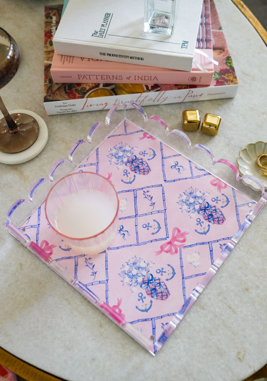 Pink acrylic tray with purple scalloped edges and blue Delta Gamma symbols on a marble surface.
