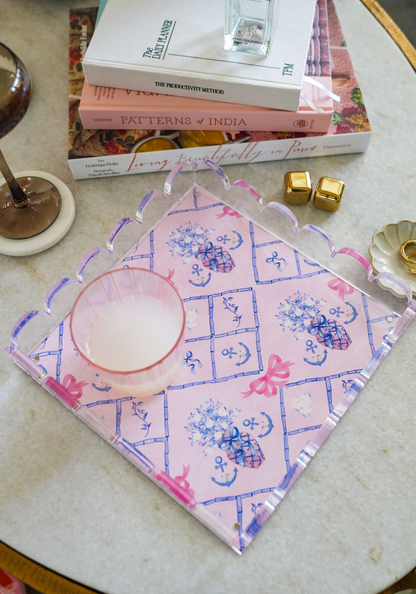 Pink acrylic tray with purple scalloped edges and blue Delta Gamma symbols on a marble surface.