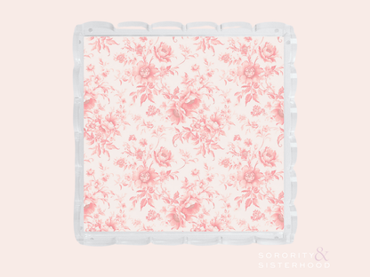 Clear acrylic tray with scalloped edges and pink floral pattern on base.