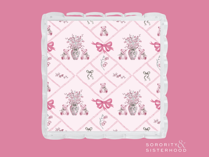 Square acrylic tray with scalloped edges, featuring pink floral bouquets, bows, and Alpha Phi symbols on a white background.