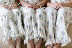 White pajama pants with purple and gold LSU Tigers fleur-de-lis print and ruffled hems.