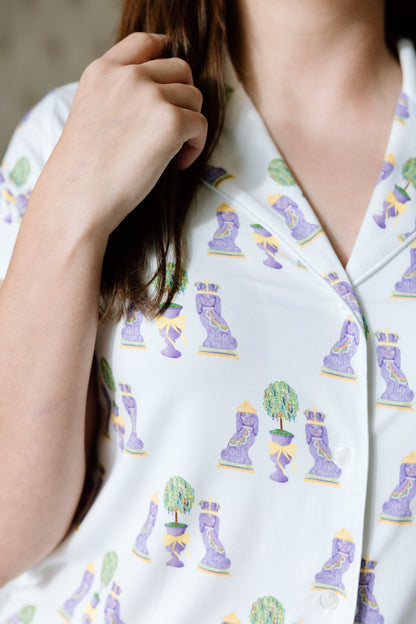 White pajama top with colorful Mardi Gras-themed print featuring masks and beads, buttoned front.