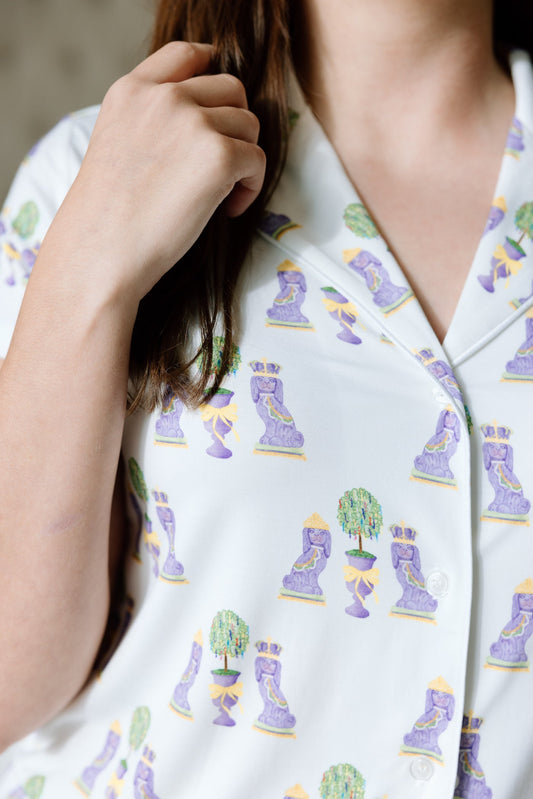White pajama top with colorful Mardi Gras-themed print featuring masks and beads, buttoned front.