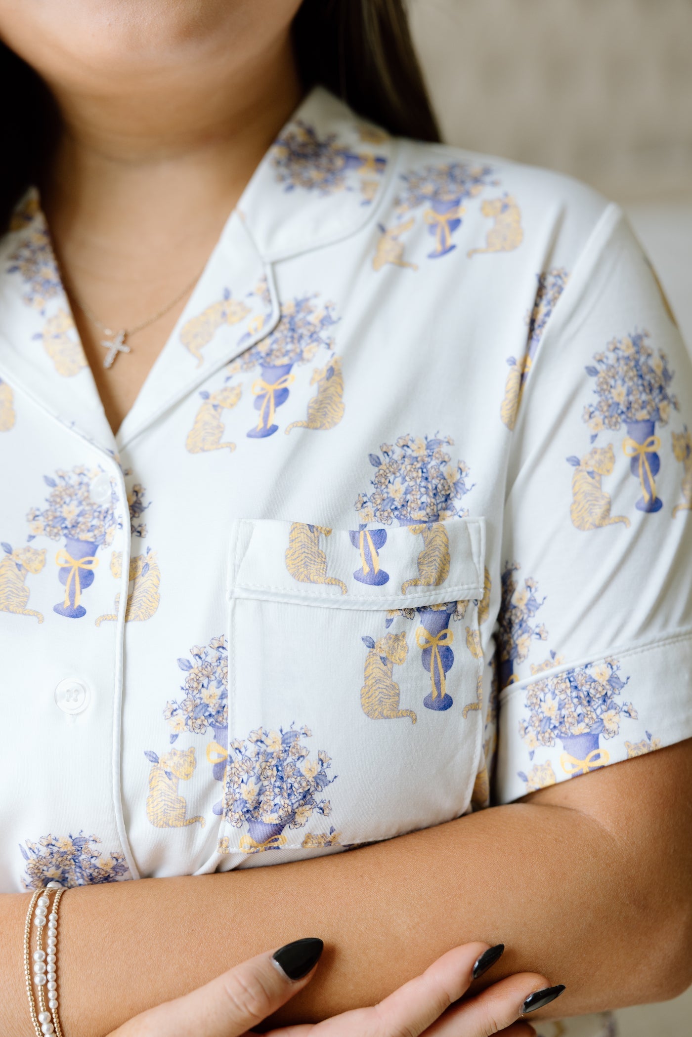 White short-sleeve pajama top with purple and gold LSU tiger floral print and chest pocket.