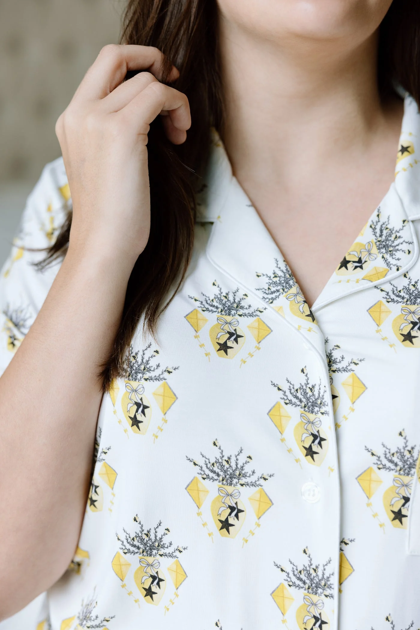 White pajama shirt with yellow diamond and black emblem pattern, notched collar, and buttons.