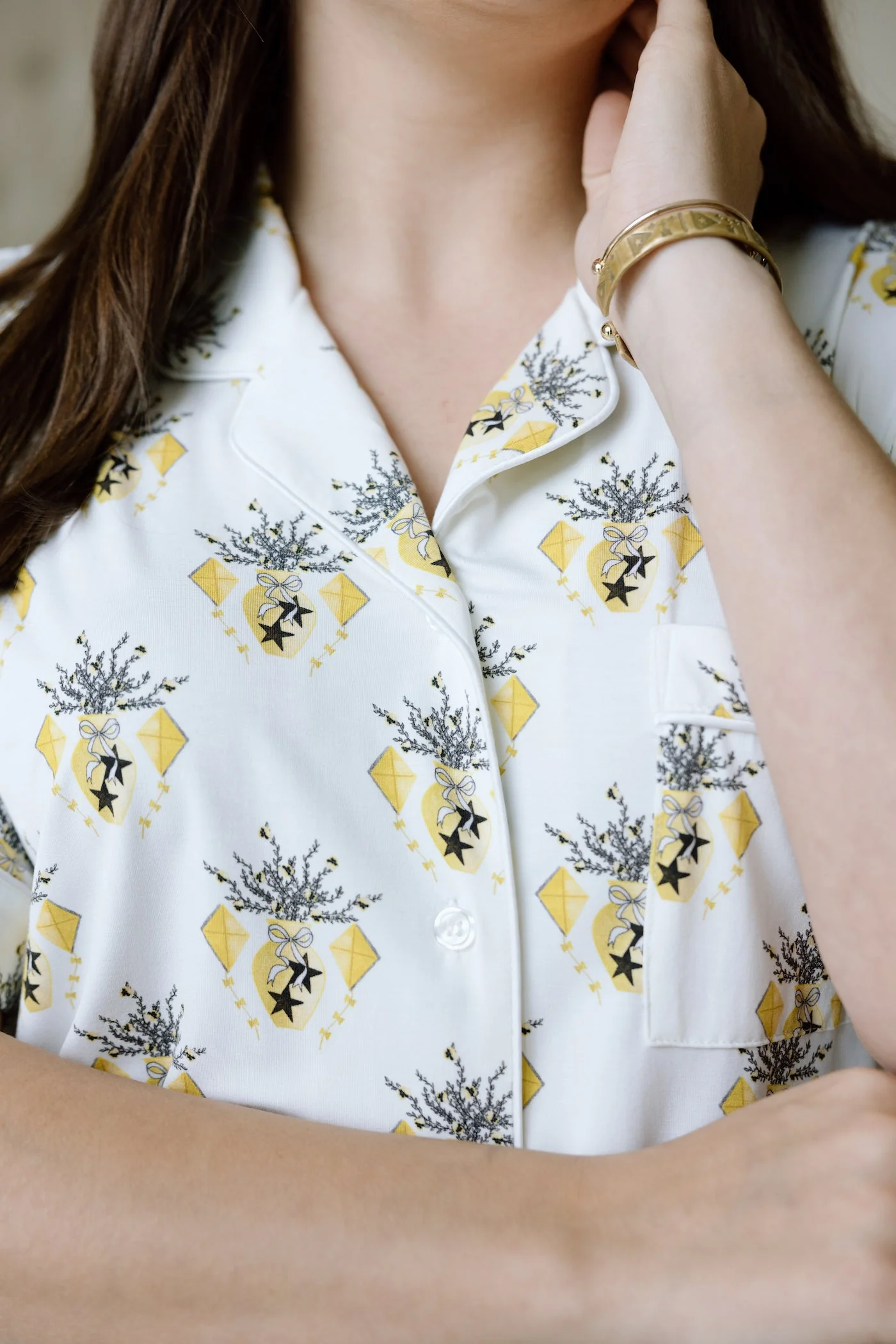 White pajama top with yellow Kappa Alpha Theta logos and black floral accents, buttoned front.