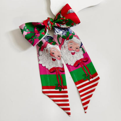 Red and green scarflette with vintage-style Santa faces, holly leaves, and red-and-white striped ends.